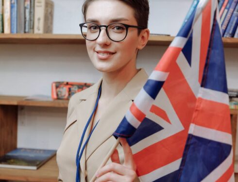 boy in white button up shirt wearing black framed eyeglasses holding blue red and white flag